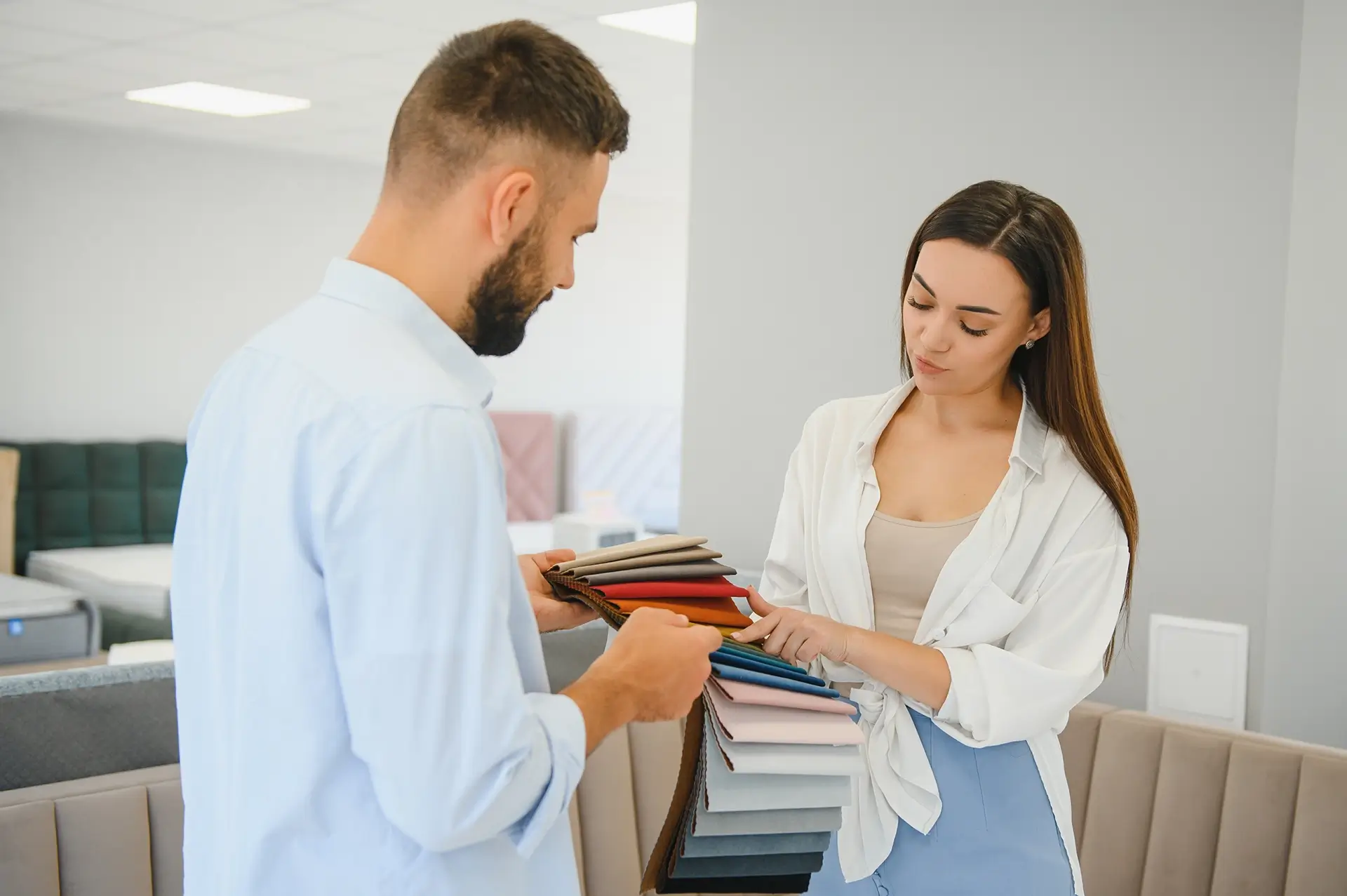 Man and a woman in a bed store looking different colour options.