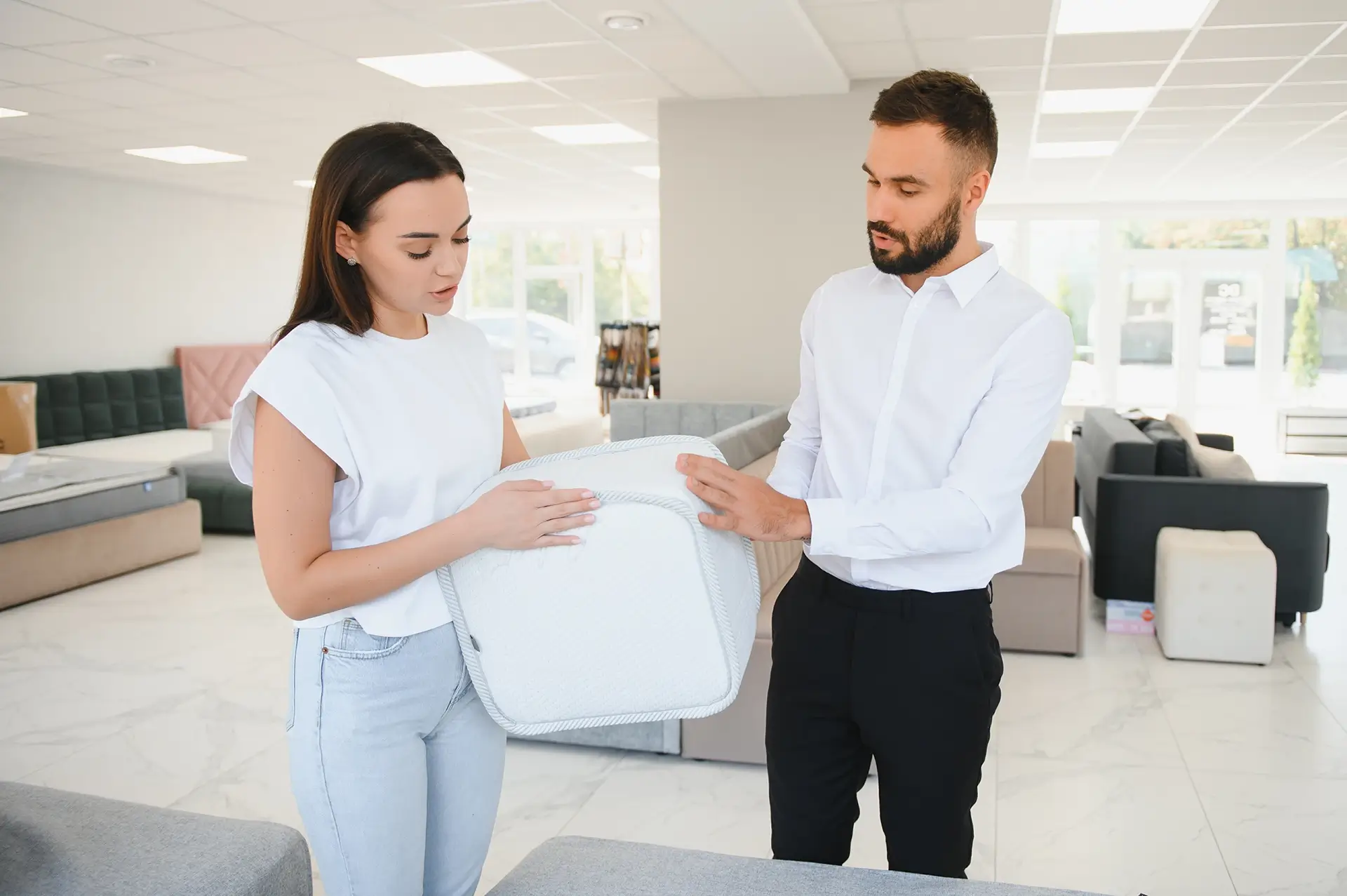 Man and a woman in a bed store looking at a test mattress.