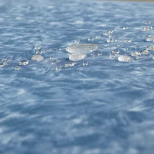 Droplets of water beading on a blue mattress.