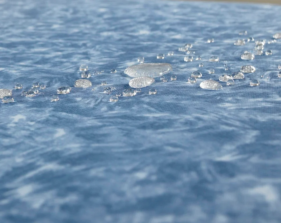 Droplets of water beading on a blue mattress.