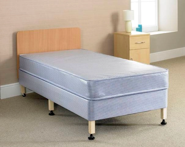 A bed with a wooden heardboard, six legs and a blue mattress.