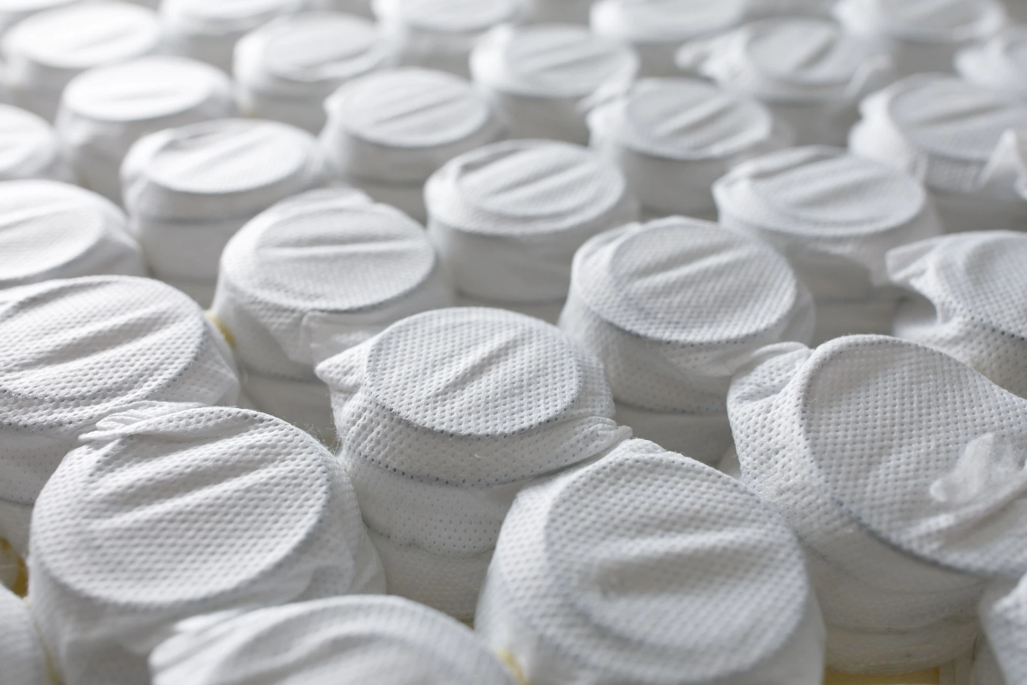 A close-up of pocket bed springs, encased with white fabric.