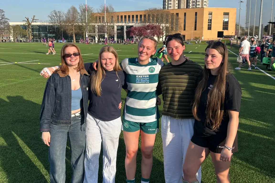 Anna in a green and white striped rugby jersey with friends.